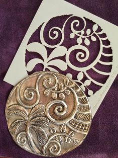 a silver coin sitting on top of a purple cloth next to a cut out card