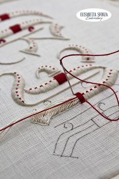 a close up of a cross stitch pattern on a piece of cloth with red thread