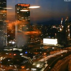 an aerial view of a city at night with lights and buildings in the foreground