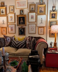 a living room filled with lots of framed pictures on the wall above a couch and coffee table