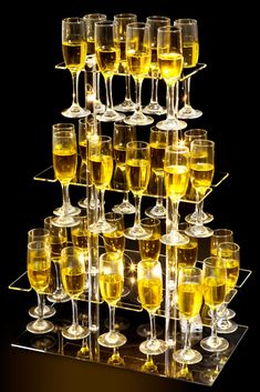 a display case filled with lots of wine glasses on top of each other and yellow liquid in the middle