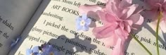 pink and blue flowers laying on top of an open book