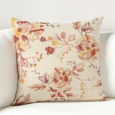 a white couch with a flowered pillow on it's back and the pillows are off to the side