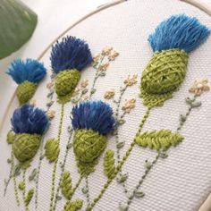 a close up of a cross stitch pattern with blue flowers and green leaves on it