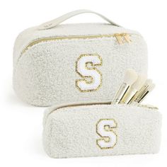 two white cosmetic bags with the letter s in gold glitter on them, one is filled with makeup brushes