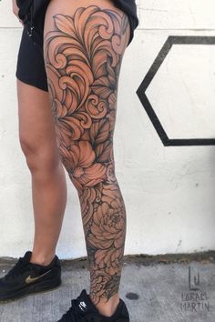 a woman's legs with tattoos on them and flowers in the middle of her leg