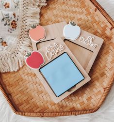 two apple shaped magnets sitting on top of a wicker basket next to an ipad