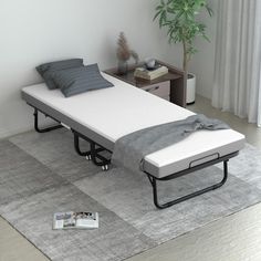 a bed sitting on top of a gray rug next to a table with a plant