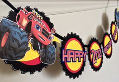 a birthday banner with a monster truck on it and happy birthday stickers hanging from the front