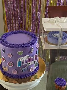 there is a purple cake and cupcakes on the table