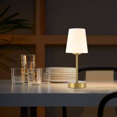 a table with glasses, plates and a lamp on it