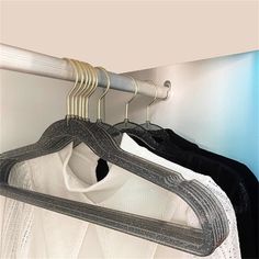 there are three shirts hanging on the clothes hangers in this room, and one is white