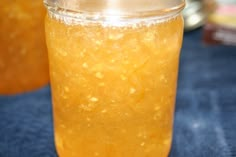 two jars filled with yellow liquid sitting on top of a blue tablecloth covered table