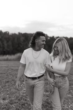 a man and woman walking through a field