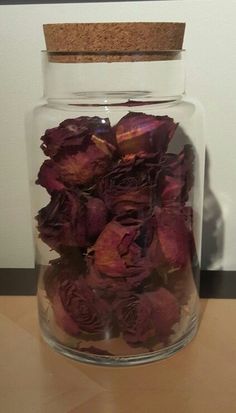 a glass jar filled with dried flowers on top of a table