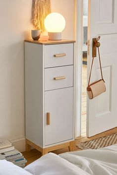 a nightstand with a lamp on top of it next to a white door and bed