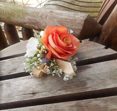 a boutonniere with an orange rose and baby's breath on it