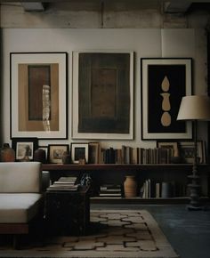 a living room filled with furniture and framed pictures on the wall above a white couch