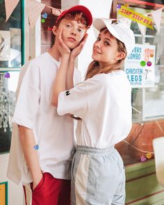 two people standing next to each other in front of a store