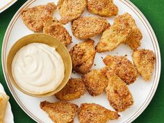 some fried food on a white plate with a small bowl of ranch dressing next to it