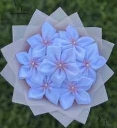 a bunch of blue flowers sitting on top of a white piece of paper in front of some green grass