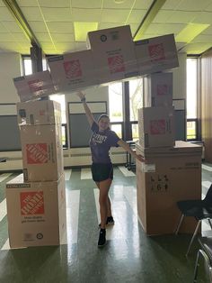 a woman is holding up boxes in an empty room