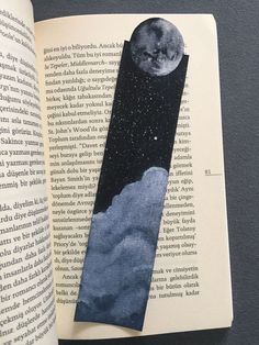 an open book with a tie on top of it next to a photo of the moon