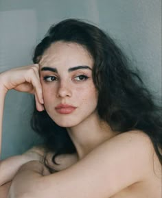 a woman with long dark hair is posing for the camera and has her hand on her head