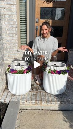 a woman standing in front of two white planters