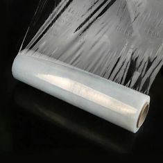 a roll of clear plastic wrap sitting on top of a table next to a black background