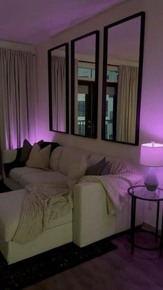 a living room filled with white furniture and purple lighting