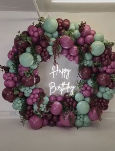 a happy birthday balloon wreath with balloons and greenery