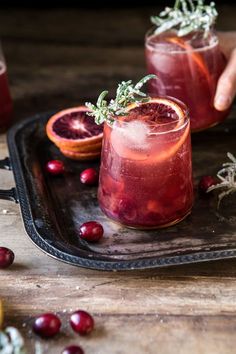 two glasses filled with blood orange and rosemary garnish on top of a tray