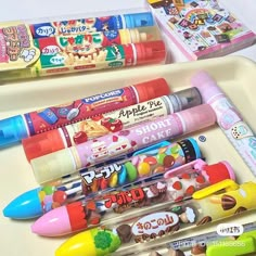 several pens and pencils are lined up on a tray next to some other school supplies