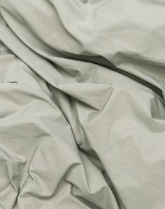 an unmade bed with white sheets and pillows