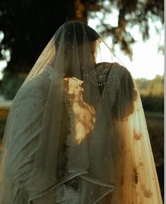 a bride and groom standing under a tree