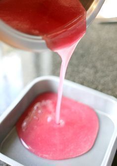 a person pouring red liquid into a container