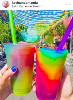 two people holding up colorful drinks in their hands