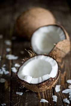 two coconuts on a wooden table with white petals