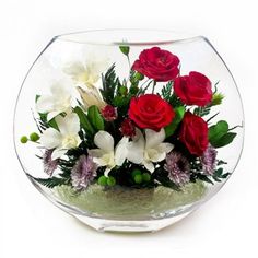 a glass bowl filled with flowers and greenery