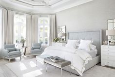 a bedroom with white furniture and large windows