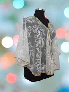 Add an extra touch of elegance to your outfit with this chic Ivory&Gold evening lace shawl, wrap  Enriched with gold ribbon detailing all around, this flowing bolero, shrug exudes sophistication and charm.  Perfect for special occasions or evening events, it looks simply dazzling under the lights.  Fastened with a gold hook and loop at the front, this cape is a versatile accessory that will elevate any look. One size fits most Bust - will fit up to 44"  Length: 55cm (21,48 Inch) Care. Hand Wash READY TO SHIP Ship to Worldwide Customs and import taxes : Buyers are responsible for any customs and import taxes that may apply. We are not responsible for delays due to customs. SHIPPING:  Please provide your PHONE NUMBER in "Note to seller" section in order to arrange delivery when submitting yo Elegant Lace Work Dupatta For Celebration, Elegant Dupatta With Lace Work For Celebrations, Elegant Party Cape-shaped Dupatta, Elegant Lace Shawl Dupatta, Elegant Party Cape Dupatta, Elegant Party Dupatta Cape, Elegant Cream Shawl For Festive Occasions, Elegant Cream Shawl For Festive Season, Elegant White Cape With Cape Sleeves