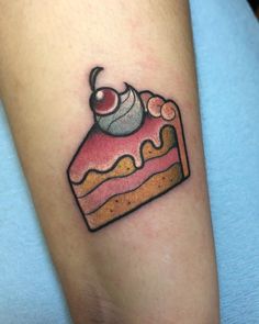 a small piece of cake tattoo on the right arm and leg, with a cherry on top