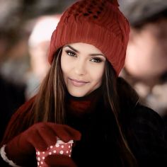 a woman with long hair wearing a red hat and gloves