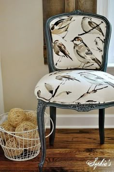 a chair with birds painted on it next to a basket of twine balls in front of a window