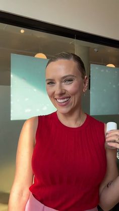 a woman in a red top is holding a white object and smiling at the camera