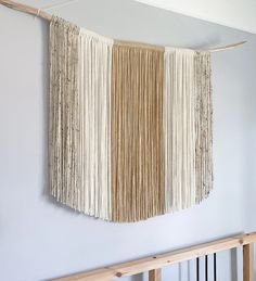 a wall hanging made out of yarn and wood sticks on top of a white wall