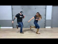 two people are dancing in an empty room with one person wearing cowboy boots and the other holding a snake