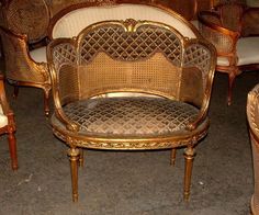 an ornately decorated settee sits in the middle of a room filled with wicker furniture