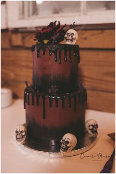 a three tiered cake with skulls and flowers on the top is covered in chocolate icing